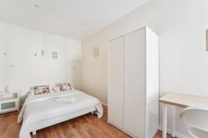 a white bedroom with a bed and a sink at Appartement RDC avec parking au centre-ville in Charleville-Mézières