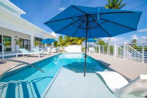 Driftwood VillageにあるCaribe Sun - Modern Villa with Pool! Walk to the Rum Point Club & Kaiboの家の隣の青い傘付きプール
