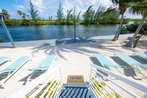Driftwood VillageにあるCaribe Sun - Modern Villa with Pool! Walk to the Rum Point Club & Kaiboのラウンジチェアとビーチサイン