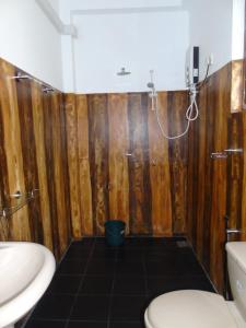 a bathroom with wooden walls and a sink and a toilet at Eco Villa - Sinharaja in Deniyaya