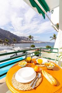 a table with plates of food on a table with a view of the ocean at Waves Views in Punta del Hidalgo