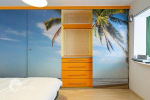 a bedroom with an orange dresser with a palm tree mural at Apartament luxos în Onești in Onești +11 photos
