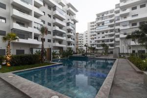 a swimming pool in front of some apartment buildings at Cozy studio with great pool views in Aïn Harrouda