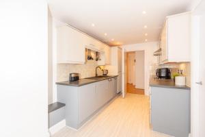 a kitchen with white cabinets and a counter top at Modern High-Floor 2BR with Terrace & Thames View in Kew Bridge