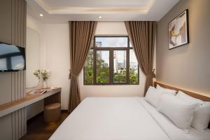 Un dormitorio con una cama blanca y una ventana. en Salux Hotel, en Da Nang