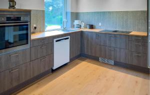 una cucina con armadi in legno e lavastoviglie bianca di 3 Bedroom Stunning Home In Fårvang a Roe