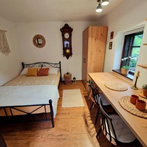 1 dormitorio con cama, mesa y reloj en Atelje Mlin Umetnin Retreat, en Šentjur