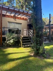 una casa con terraza y un árbol en el patio en PURA VIDA 3, en Mar de las Pampas