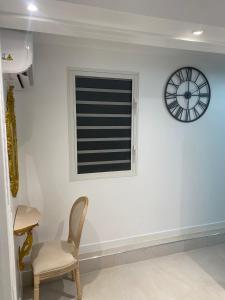 a chair and a window with a clock on a wall at La petite racine in Sainte-Marie