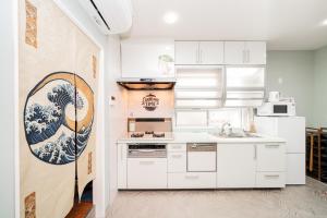 Una cocina con gabinetes blancos y un cuadro en la pared. en Spacious 3-Story House with 2 Baths, 7 min to Metro direct to Akihabara Ueno Ginza, en Tokio
