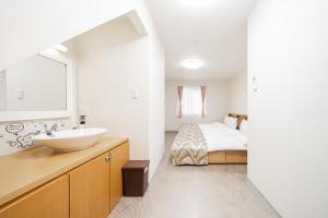 Un baño blanco con lavabo y cama. en Spacious 3-Story House with 2 Baths, 7 min to Metro direct to Akihabara Ueno Ginza, en Tokio