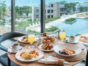 a table with plates of food and drinks and a pool at Sofitel Barú Cartagena in Cartagena de Indias