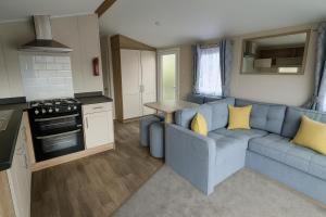 a living room with a blue couch in a caravan at Lyons Sunnysands Holiday Park - Holiday Accommodation 13733 in Llanddwywe