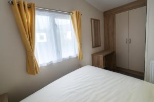 a bedroom with a white bed and a window at Lyons Sunnysands Holiday Park - Holiday Accommodation 13733 in Llanddwywe