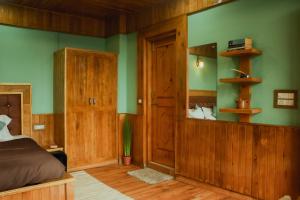 a bedroom with green walls and a bed and wooden furniture at Khaapus Home Naggar in Nagar
