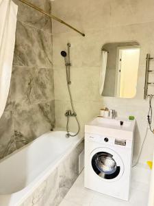 a bathroom with a tub and a washing machine at Capital Park Flowers 5A in Astana