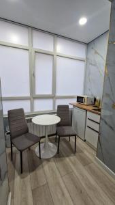 a kitchen with two chairs and a table and some windows at Апартаменты в ЖК Атамура in Karagandy