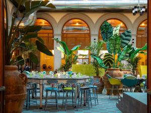 フィレンツェにある25hours Hotel Florence Piazza San Paolinoのテーブルと椅子と植物のあるレストラン