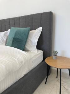 a bed with a gray headboard next to a table at Urban Sud Residence in Giroc