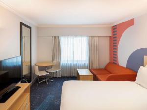 a hotel room with a bed and a couch and a table at ibis Styles Sydney Central in Sydney