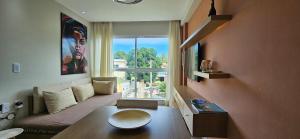 a living room with a couch and a large window at Na Praia Flats Centro AD 108 in Porto De Galinhas