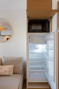 a refrigerator with its door open with a microwave at La Loggia du Triton - Superbe T2 avec parking in Le Grau-du-Roi