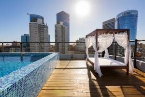 a bed on the roof of a building next to a pool at Palladium Business Hotel in Montevideo