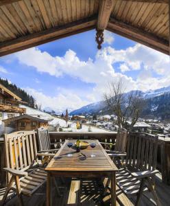 Buccara Apartments Kitzbühel في كتسبويل: طاولة وكراسي خشبية على سطح مع اطلالة