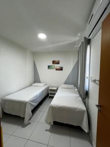 two beds in a room with white walls at APARTAMENTO EM PORTO DE GALINHAS in Recife