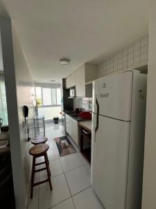 a kitchen with a refrigerator and a table and a stool at APARTAMENTO EM PORTO DE GALINHAS in Recife