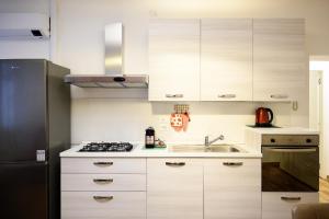 a kitchen with white cabinets and a sink and a refrigerator at Elegante appartamento in Centro storico - Vista sul corso principale - Spazioso , WiFi veloce, posizione top in Pordenone