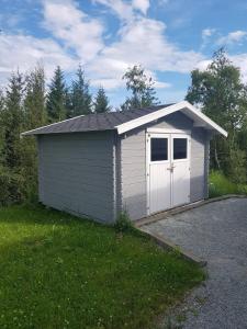 波多Huset i skogskanten i Bodø的草上有一扇门的白色车库