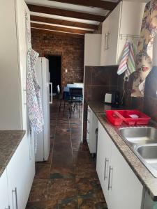 a kitchen with white cabinets and a brick wall at Come Again Self Catering in George +14 photos