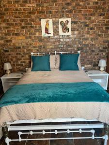 a bedroom with a large bed with a brick wall at Come Again Self Catering in George