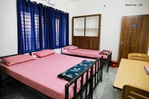 two beds in a room with blue curtains at Ganga Homes Rooms Only in Trichūr