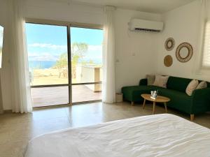 a living room with a green couch and a large window at Vista lake - Kinneret view in Tel Kazir