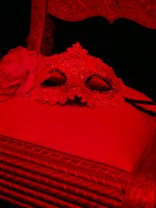 a red mask sitting on top of a bed at Gîte romantique Le GLAMOUR in Mazé