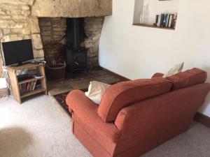 een woonkamer met een bruine bank en een open haard bij Hope Cottage in Stroud
