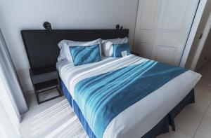 a bed with blue and white sheets and pillows at Cyan Recoleta Hotel in Buenos Aires