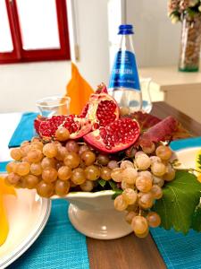 a bowl of grapes and pomegranates on a table at Pausania Temple il pavone smeraldo in Tempio Pausania