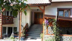 uma casa com escadas que levam à porta da frente em Pensiunea Piatra Mandrutului em Scarisoara