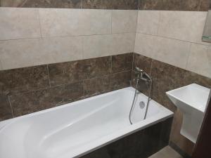 y baño con bañera blanca y lavamanos. en MV Grand Hotel, en Apenkwa
