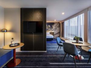 a hotel room with two tables and a bed at Novotel Melbourne Preston in Melbourne
