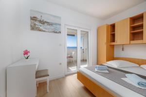 Un dormitorio con una cama y un escritorio y una ventana. en Apartmani Panorama, en Igrane