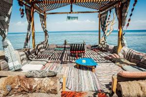 a gazebo with chairs and a table and the ocean at Gammal Boutique Camp in Nuweiba‘ el Muzeinah