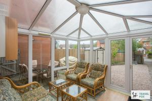 a conservatory with chairs and a table at Sarah's House BBQ Parking 10mins To Alton Towers in Rocester