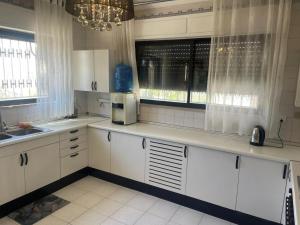 a kitchen with white cabinets and a sink and windows at Jubaiha Stars in Al Jafr