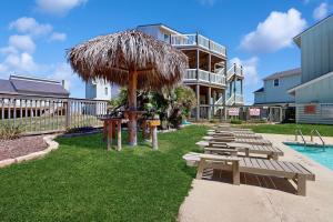a row of picnic tables and an umbrella next to a pool at Lost Colony #5 in Port Aransas
