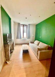 a living room with a couch and a green wall at Appartement proche des transports in Villeurbanne