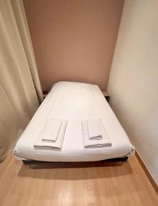 a white bed in a small room with a wooden floor at Appartement proche des transports in Villeurbanne